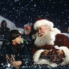 a little boy sitting next to santa clause