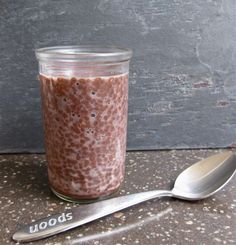 a glass jar filled with food next to a spoon on top of a stone counter