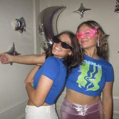 two young women are posing for the camera with their arms around each other and one is wearing pink glasses