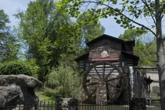 an old water mill in the middle of a forest with rocks and trees around it