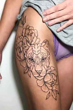 a woman's thigh with flowers and a wolf tattoo on the side of her leg