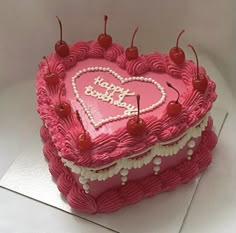 a heart shaped birthday cake with cherries on the top, and happy birthday written in pink frosting