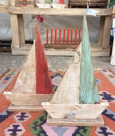 two wooden sailboats sitting on top of a rug in front of a table and bench