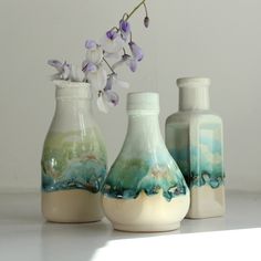 three vases with flowers in them sitting on a table