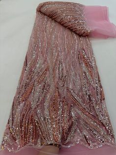 a pink dress with sequins on it laying on a white surface next to a piece of cloth