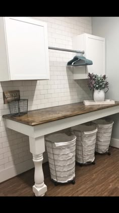 a kitchen counter with three trash cans under it