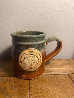 a brown and green mug sitting on top of a wooden table