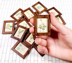 a hand holding a small wooden box with pictures on it