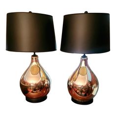 two shiny glass lamps with black shades on each one and a brown shade on the other