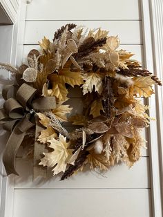 a wreath hanging on the side of a door decorated with dried leaves and foliages