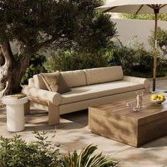 a couch and coffee table outside under an umbrella