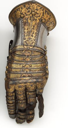 an ornate gold and silver glove with intricate designs on the back, worn by men