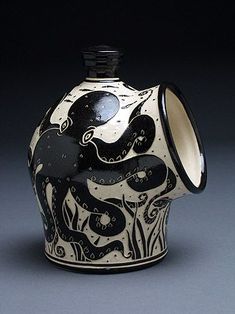 a black and white vase with an octopus design on the front, sitting on a gray surface