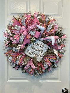 a pink and white wreath on the front door