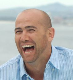 a bald man with his mouth open and tongue hanging out to the side, laughing