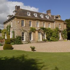 a large brick building with lots of windows on the front and side of it, surrounded by greenery