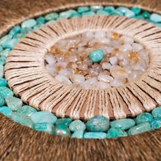 a close up of some beads and stones on a woven table cloth with a circular design in the middle