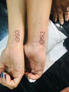 two people are holding hands with tattoos on their feet and one has a heart in the middle