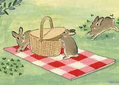 three rabbits are sitting on a picnic blanket with a basket in the foreground, and another rabbit is running towards it