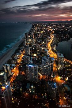 an aerial view of the city lights and beach at night, with ocean in the background