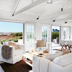 a living room filled with white furniture and windows