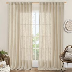 a living room with white curtains and wicker chairs in front of the window,