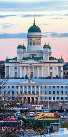 a large white building with a green dome on top and many boats in the water around it