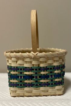 a woven basket with a wooden handle sitting on a bed