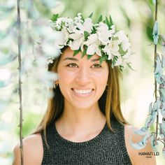 a woman with flowers in her hair smiling for the camera while sitting on a swing