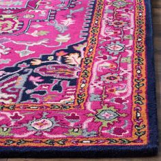 a pink and blue rug with an ornate design on the bottom, sitting on a wooden floor