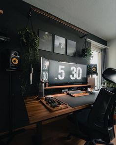 a desk with a monitor and speakers on top of it in front of a window