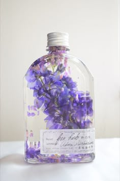 purple flowers are in a clear glass bottle