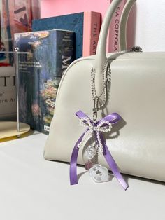 a white purse with a purple ribbon around it