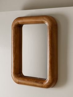 a mirror mounted to the side of a white wall next to a wooden framed object