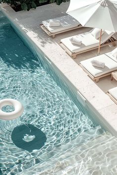 an empty swimming pool with lounge chairs and umbrellas