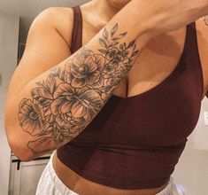 a woman taking a selfie in the mirror with flowers on her arm and shoulder