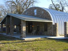 a stone building with a metal roof in the grass