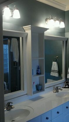 a bathroom with two sinks and three mirrors on the wall above them is lit by lights