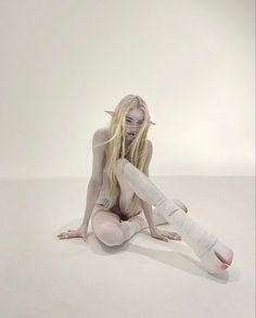 a naked woman sitting on the ground with her leg wrapped up and bandages around her ankles