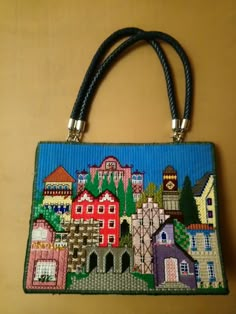 a handbag with a city scene on the front and side, hanging from a wall