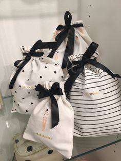 three bags with black and white designs on them sitting on a glass shelf in front of a mirror