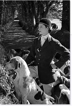 a black and white photo of a man riding on the back of a horse next to dogs