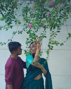 a man standing next to a woman under a tree