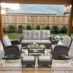 an outdoor living room with wicker furniture and wood flooring in front of a wooden fence