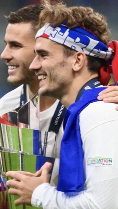 two soccer players are holding the trophy together