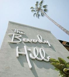 the sign on the building says the beverly hills with two palm trees in the background