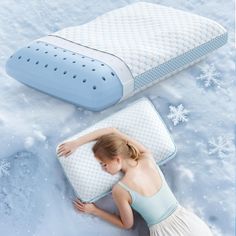 a woman laying on top of two pillows in the snow