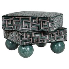 two green balls sitting on top of each other next to a black and white ottoman