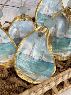 four sailboats are on the water in this decorative ornament, which is hanging from a wicker basket