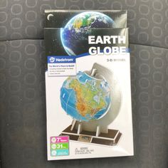 the earth globe is sitting on top of a stand in front of a gray seat